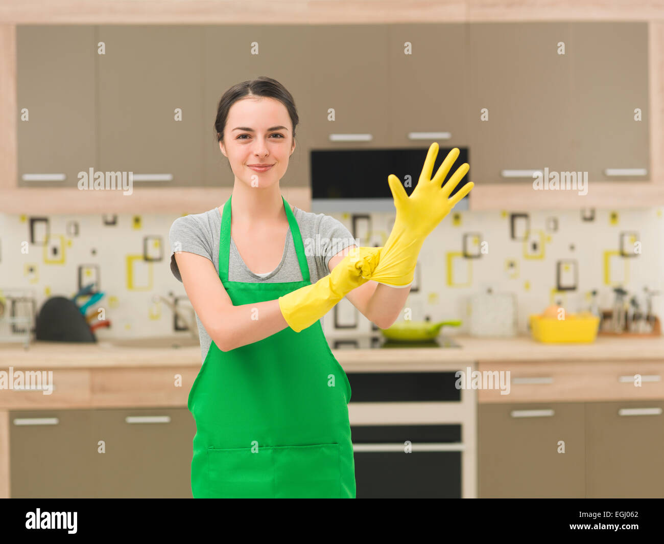 young happy woman putting rubber gloves and getting ready for cleaning ...