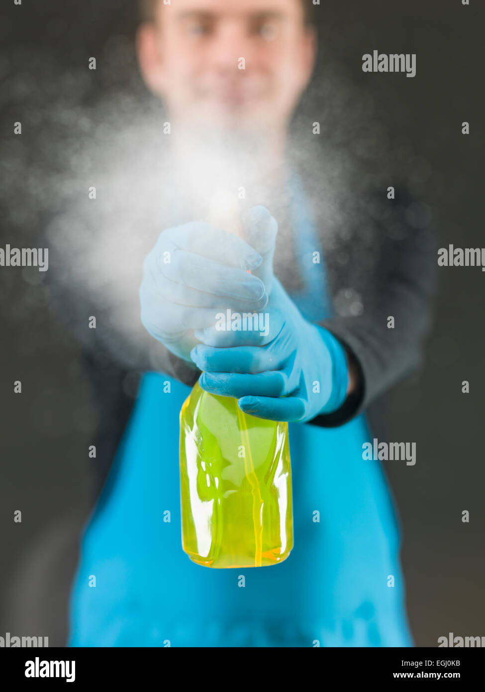 cleaning worker spraying liquid detergent on window surface in front of him Stock Photo