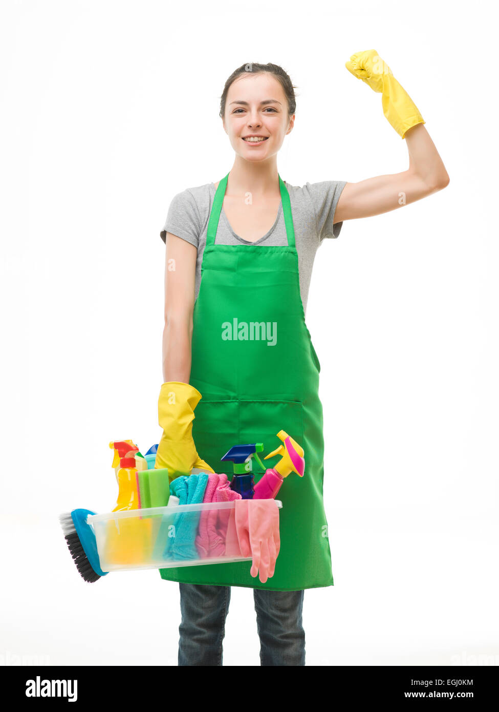young caucasian woman holding cleaning supplies and flexing her arm muscles against white background Stock Photo