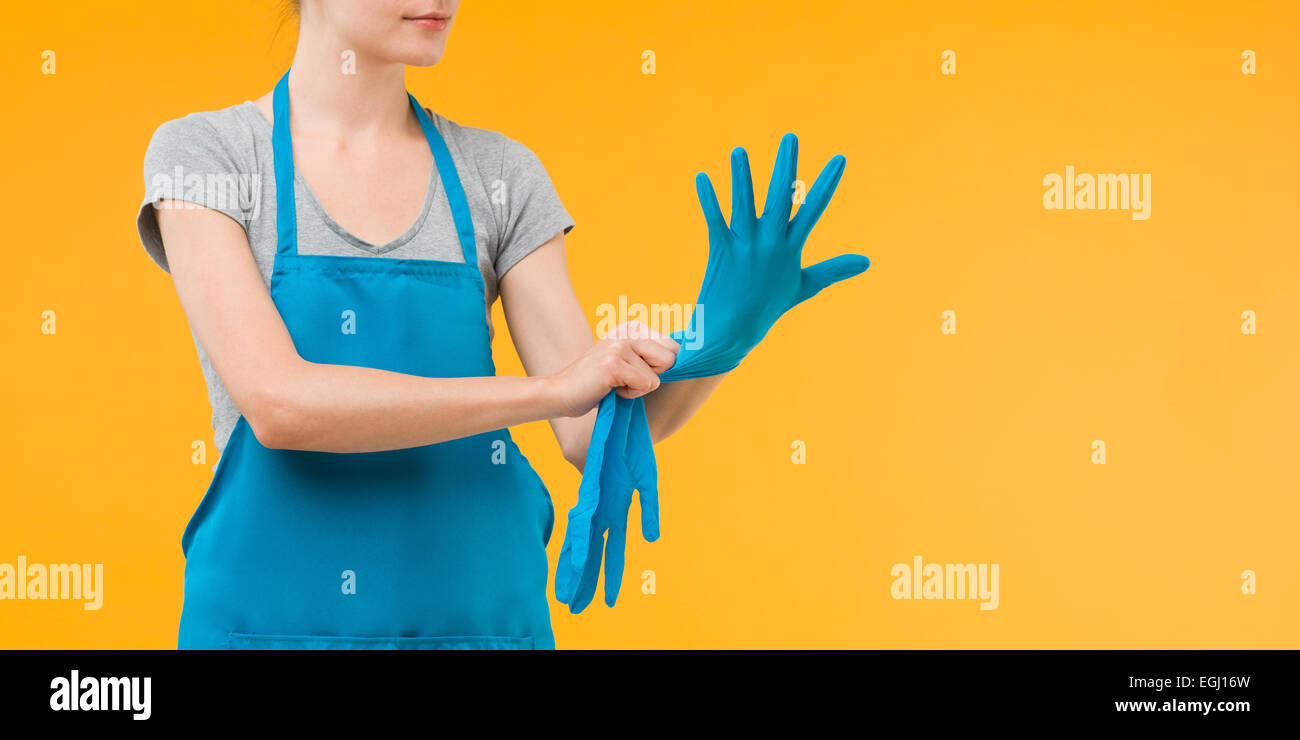 woman getting ready for spring cleaning, putting on blue rubber gloves ...