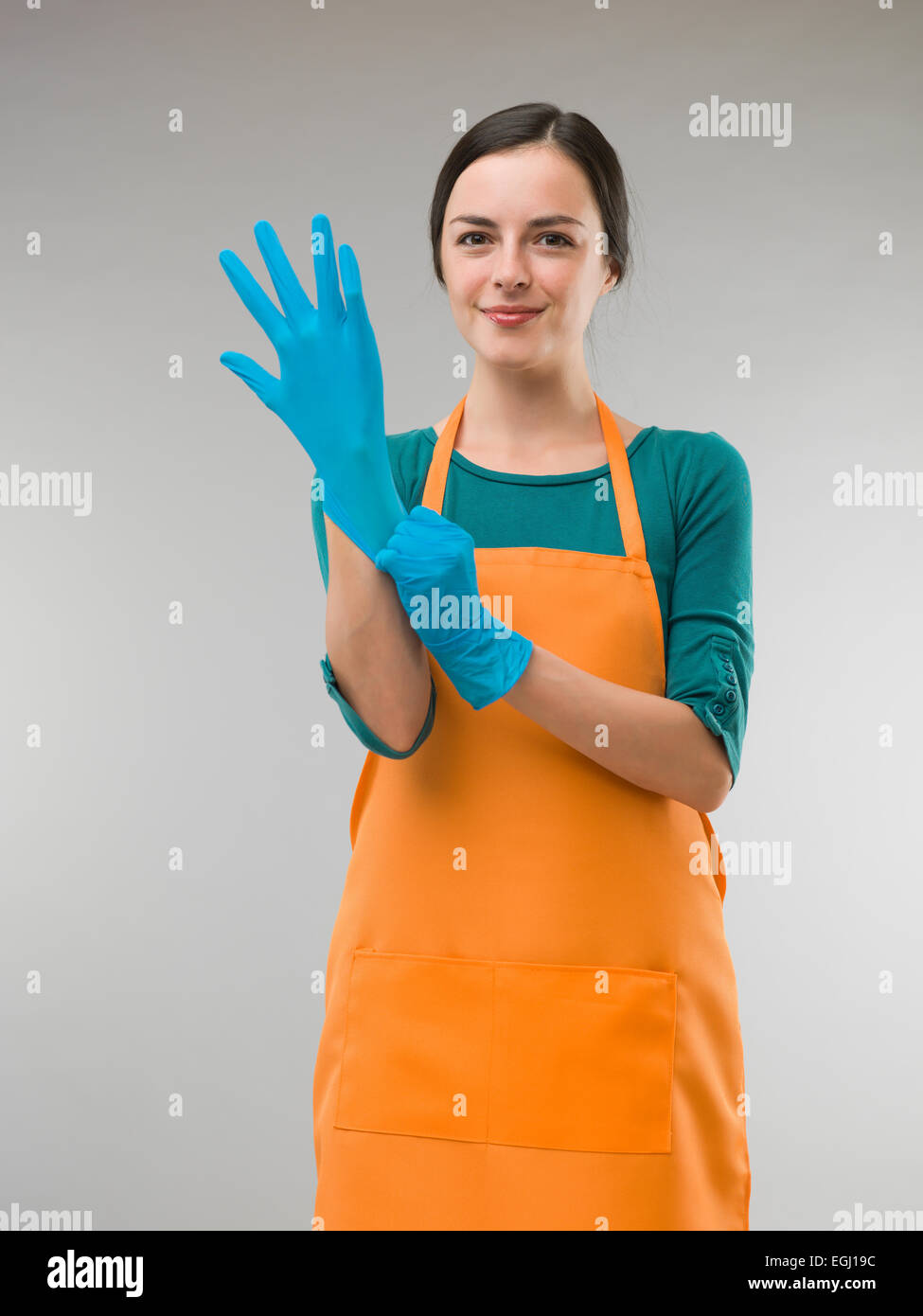 young happy cleaning woman putting on rubber gloves Stock Photo
