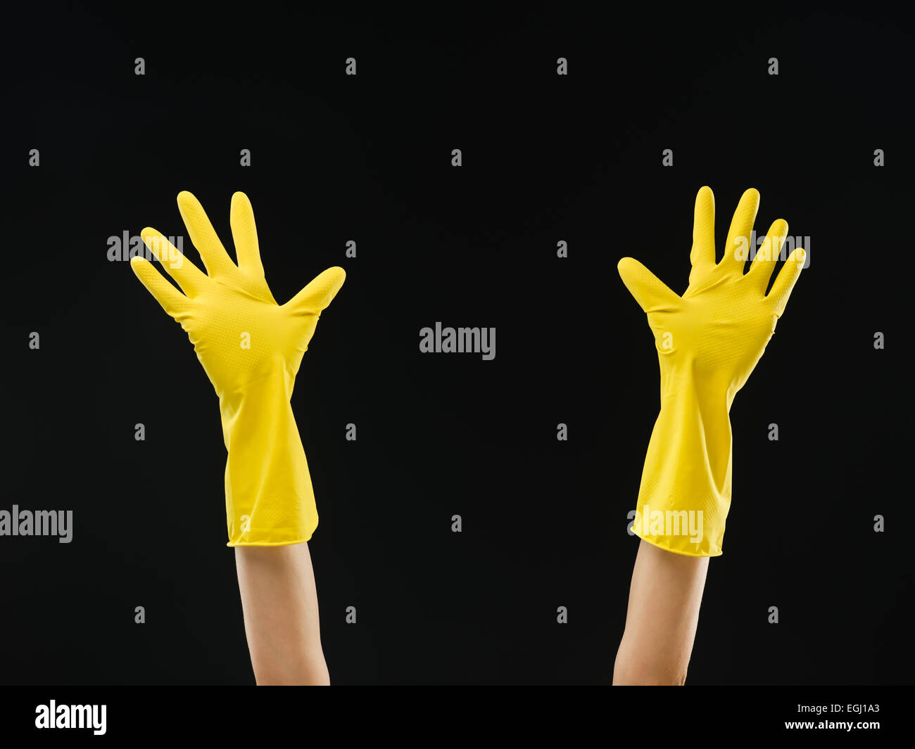 hands up with yellow rubber gloves with open palms on black background Stock Photo