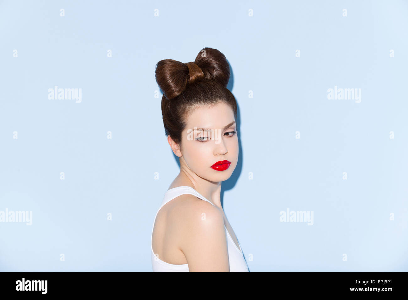 Portrait of a young woman in front of blue wall Stock Photo - Alamy