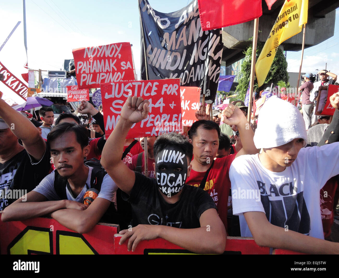 Militant protesters chanting slogans raise their fists during a rally at EDSA highway, held on the 29th anniversary of the 1986 People Power revolution. The protesters were blocked by police from reaching the police headquarters where they intended to form a 'human chain' from the headquarters to EDSA Shrine. Credit:  Richard James Mendoza/Pacific Press/Alamy Live News Stock Photo