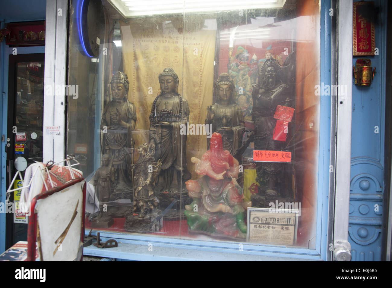 Store window in Chinatown with Buddhist & Taoist statuary. Canal Street, NYC. Stock Photo