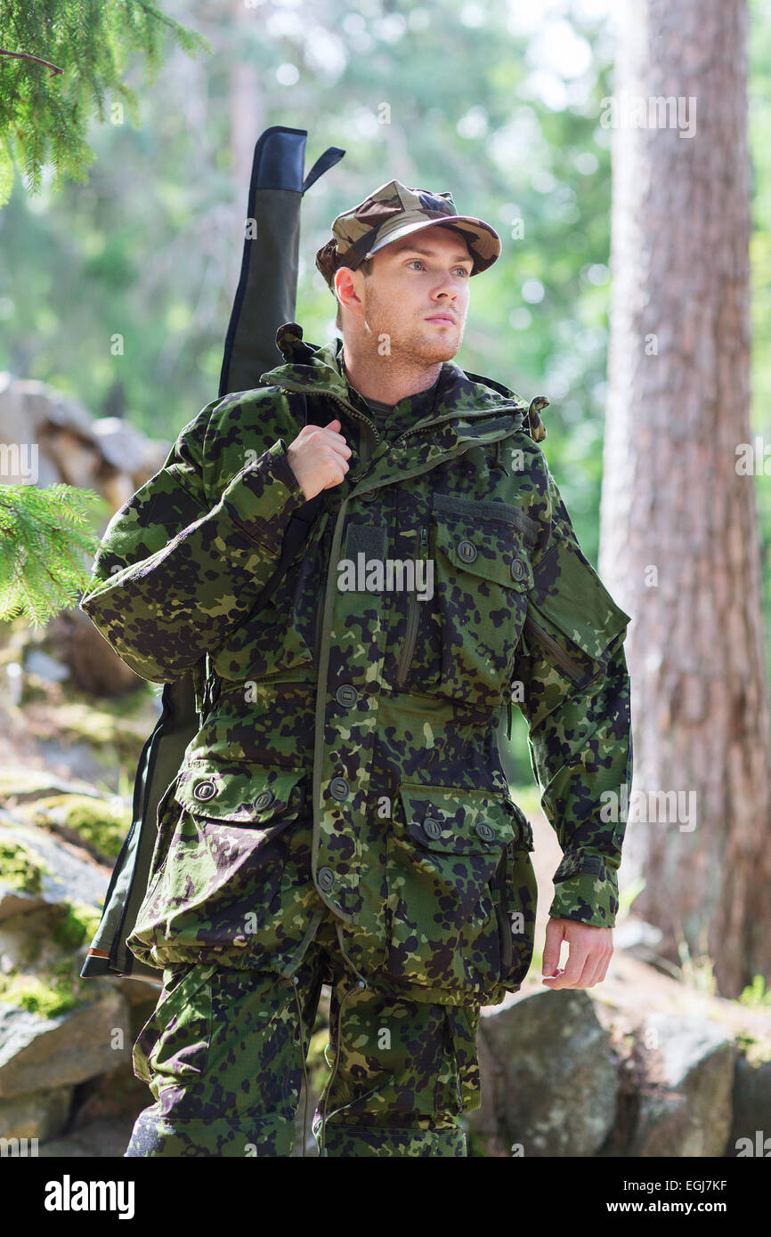 young soldier or hunter with gun in forest Stock Photo