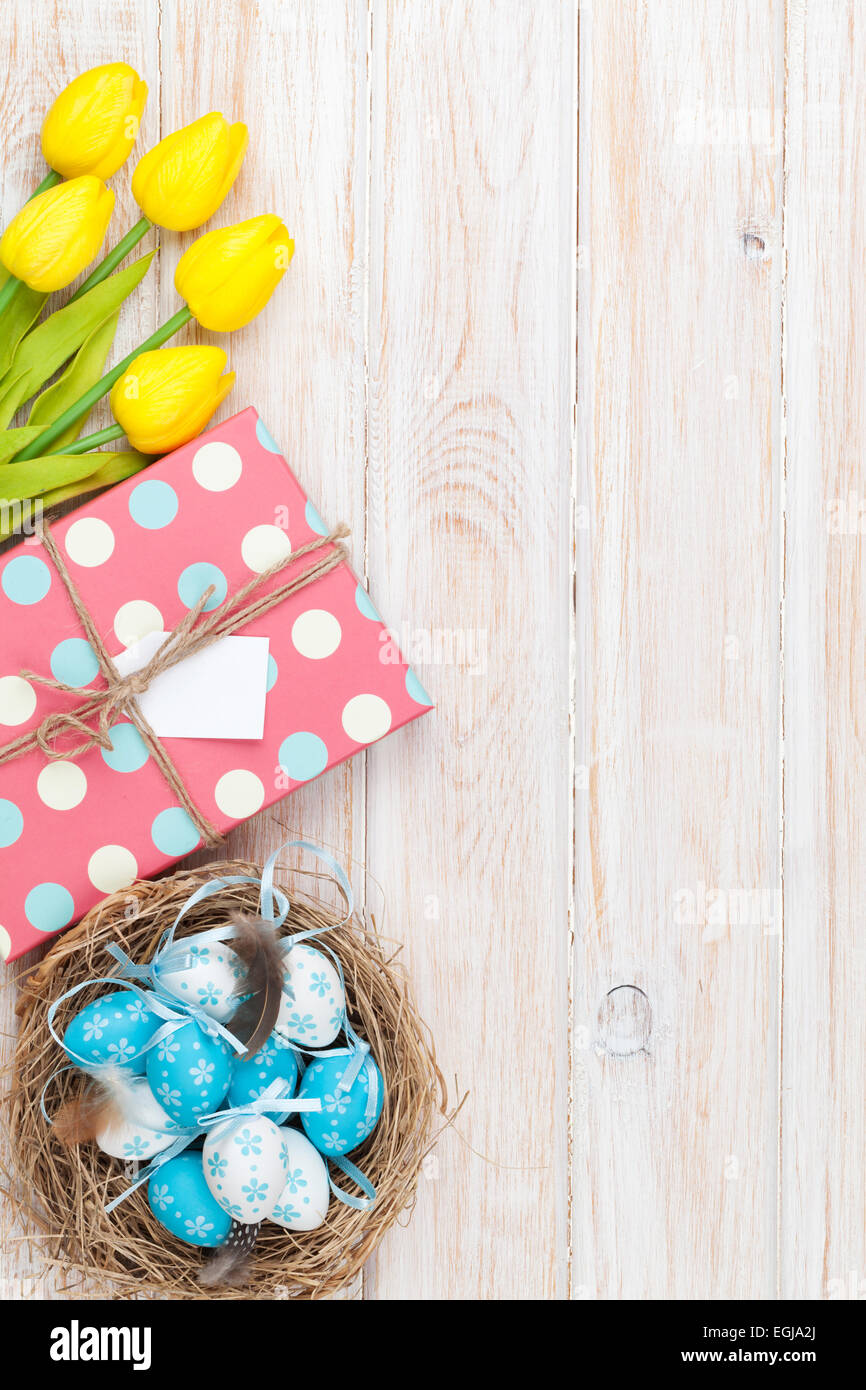 Easter background with blue and white eggs in nest, yellow tulips and ...