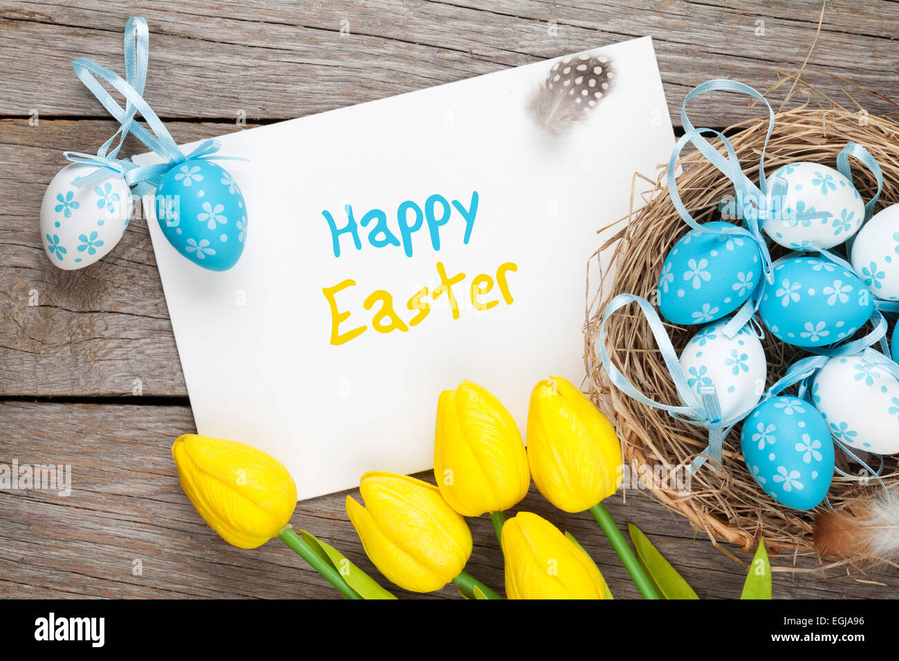 Easter greeting card with blue and white eggs and yellow tulips over ...