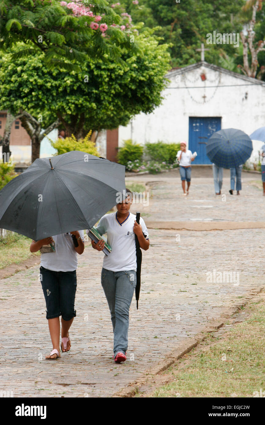 Taking shade from the heat of the day, girls hiding under umbrella Stock Photo