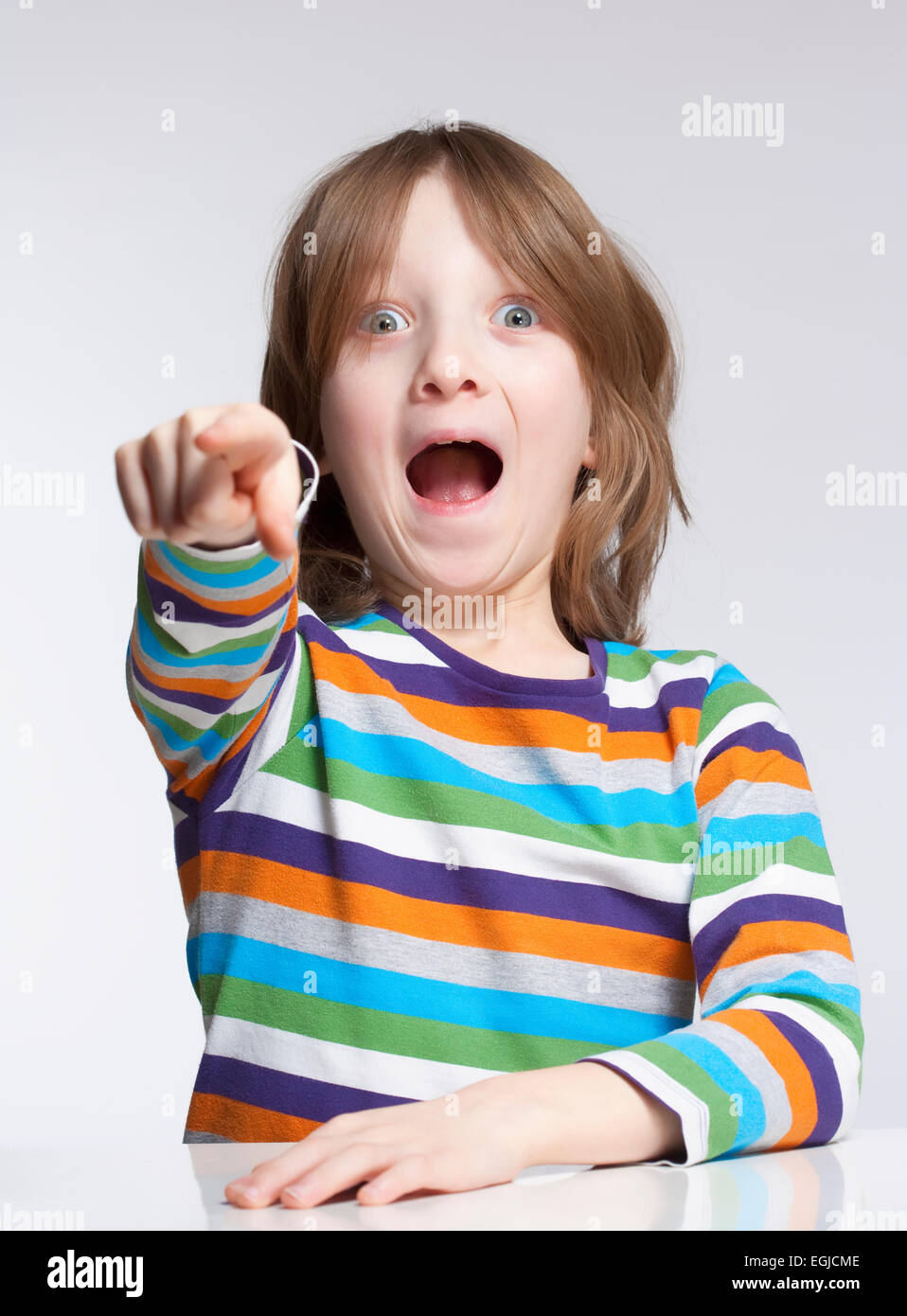 Boy with Blond Hair Pointing with his Mouth Open Stock Photo