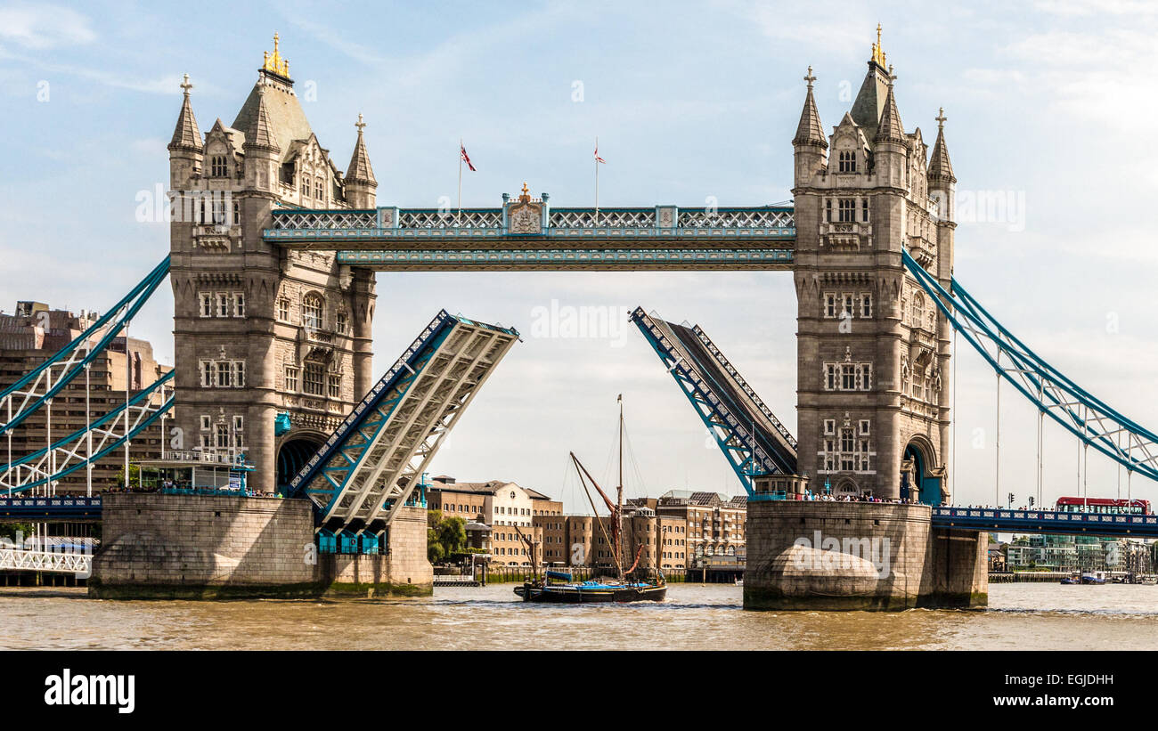 London Tower Bridge, London England; the suspension bridge is rising to let a single mast sailing boat to pass. Stock Photo