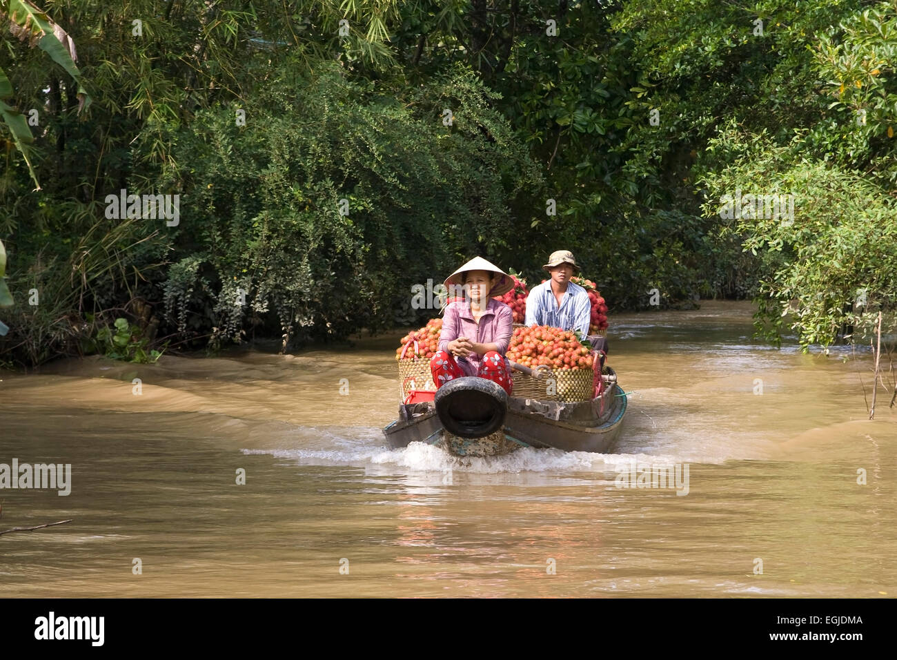 Two Vietnamese drive on a wooden boat market in a side channel of the Mekong, Mekong Delta, Vietnam, Asia Stock Photo