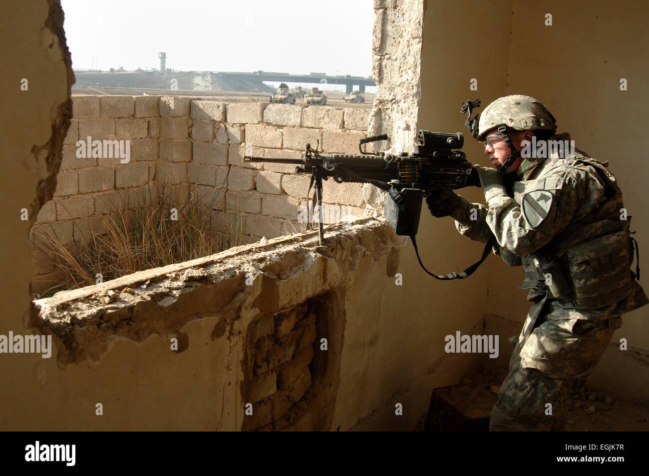 A US soldiers from 1st Cavalry Division keeps watch for insurgent targets from a window during a search for a missing soldier February 23, 2007 in Baghdad, Iraq. Stock Photo