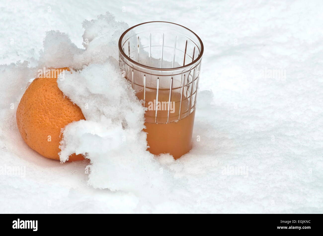 Orange fruit and orange juice refrigerate in the snow-drift at garden, Sofia, Bulgaria Stock Photo