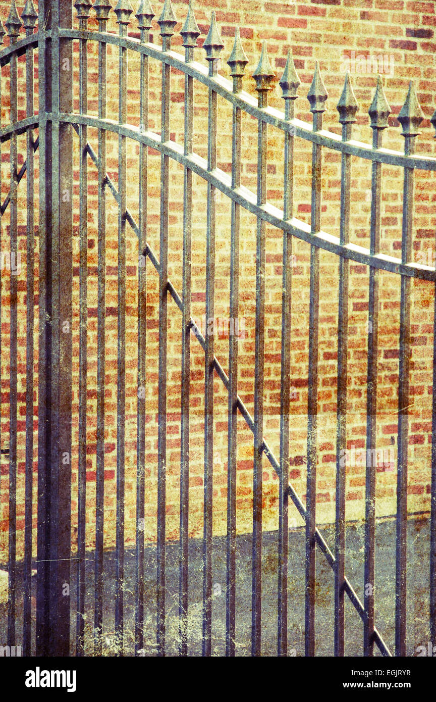 Iron gate in front of brick wall. Aged/grunge texture applied to photo for dramatic effect Stock Photo