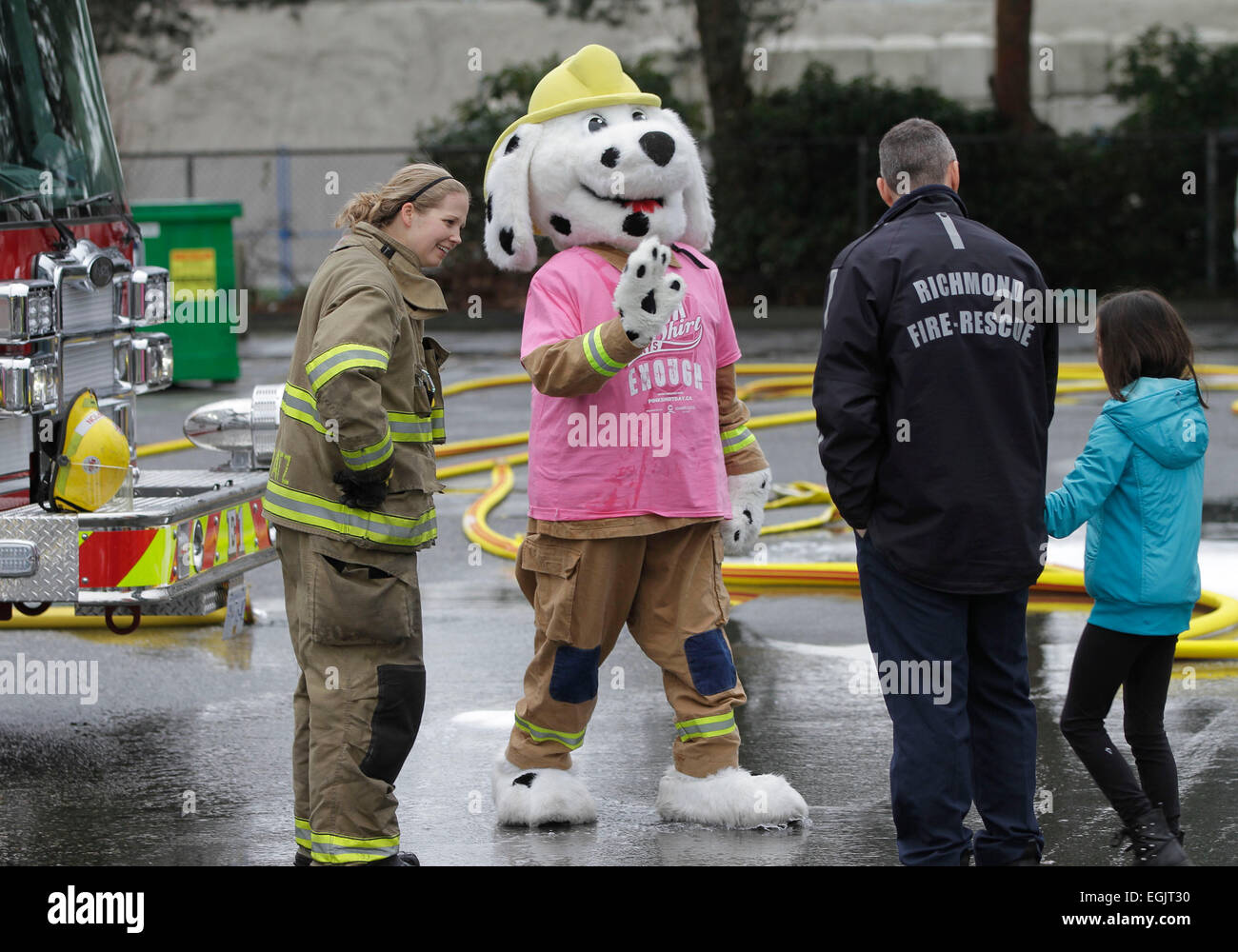 Richmond, Canada. 25th Feb, 2015. A mascot of fire hall wearing pink shirt to support anti-bullying greets a schoolgirl at a fire hall in Richmond, Canada, Feb. 25, 2015. People from different organizations and schools across Canada wear pink shirts on the annual Pink Shirt Day to raise awareness and support anti-bullying. © Liang Sen/Xinhua/Alamy Live News Stock Photo