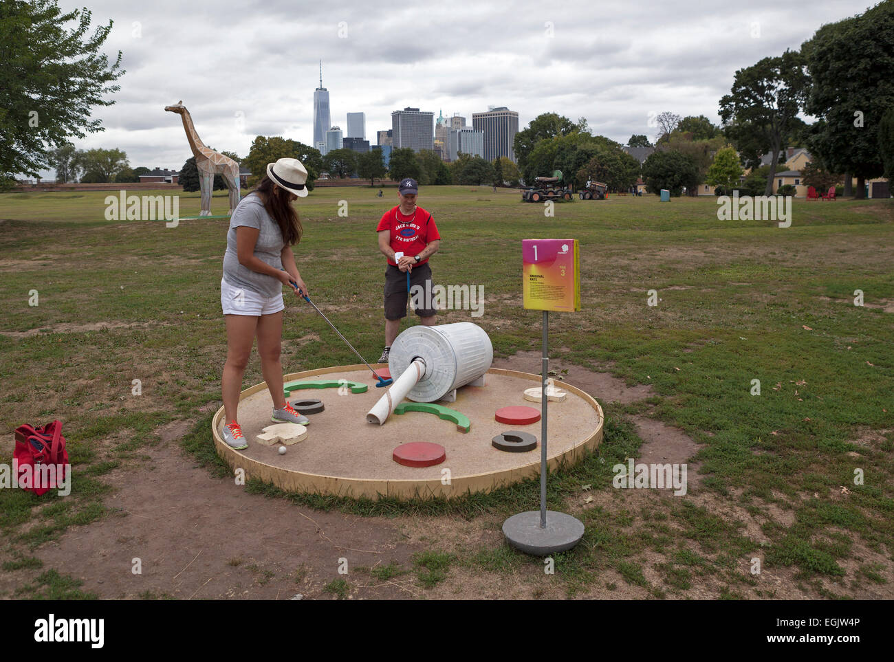 People enjoy a game of miniature golf with the skyline of New York City. in the background. Stock Photo