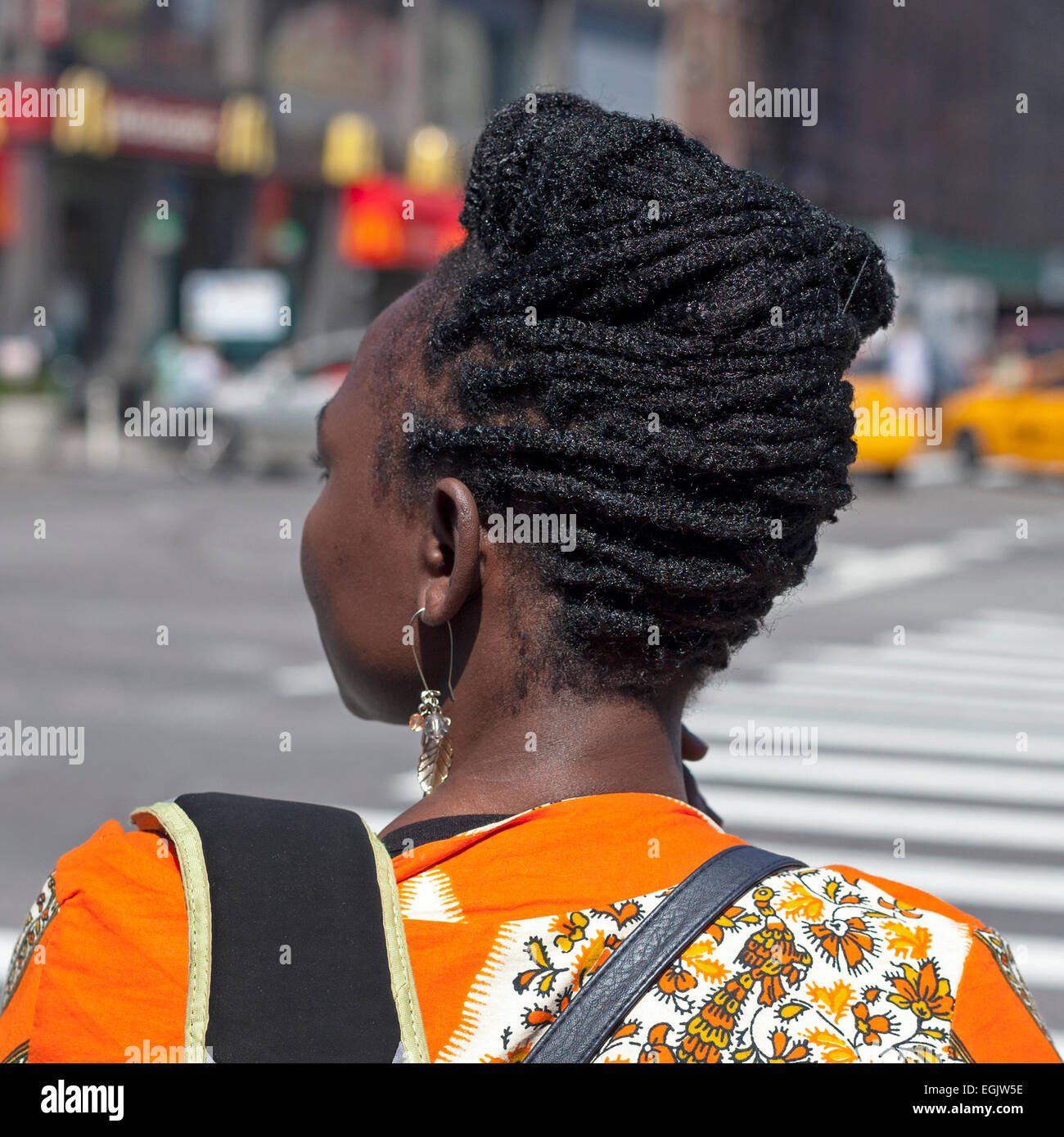 A woman waits at a corner in Manhattan, New York City, USA. Stock Photo