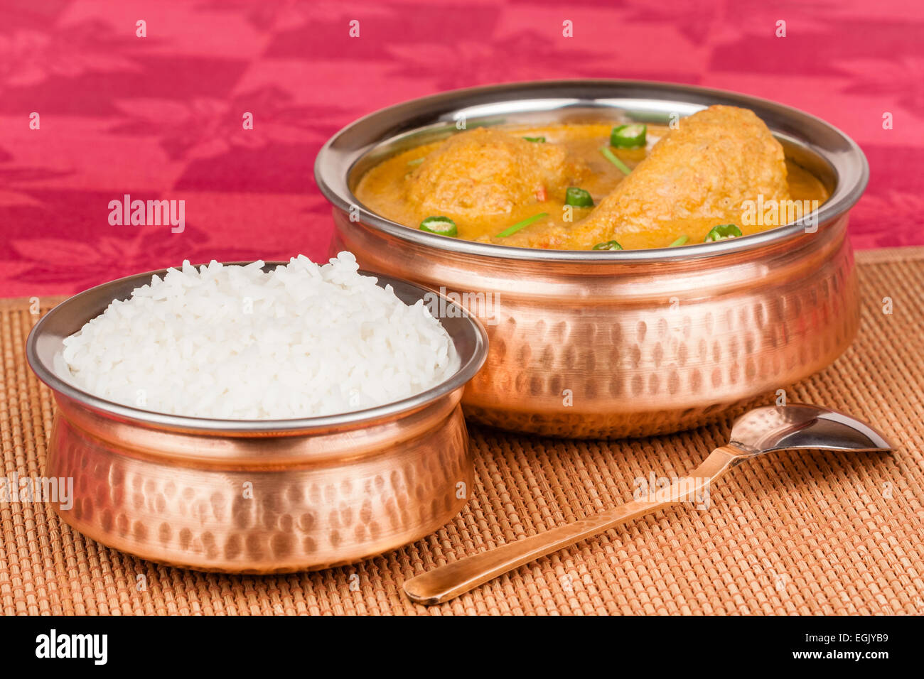 Indian chicken curry served with rice in authentic copper utensils