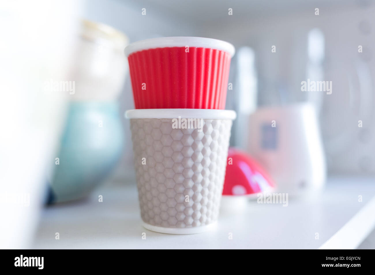 different colors of design cups in bright kitchen on shelf Stock Photo