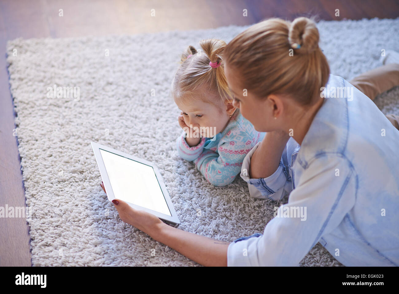 Young woman using touchpad for teaching her preschool daughter Stock