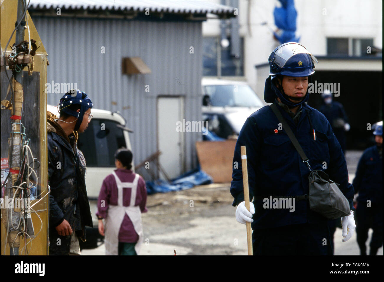 April, 1995, Kamikuisshiki Mura, Japan - A member Aum wearing a headgear walks behind a riot police trooper during a raid on the cult's facility - No. 2 Satyam - on the foot of Mt. Fuji in April 1995. Police found explosives, chemical weapons and biological warfare agents and a Russian Mil Mi-17 military helicopter. On the morning of 20 March 1995, Aum members released sarin in a coordinated attack on five trains in the Tokyo subway system, killing 13 commuters, seriously injuring 54 and affecting 980 more. Some estimates claim as many as 6,000 people were injured by the sarin. (Photo by Haruy Stock Photo