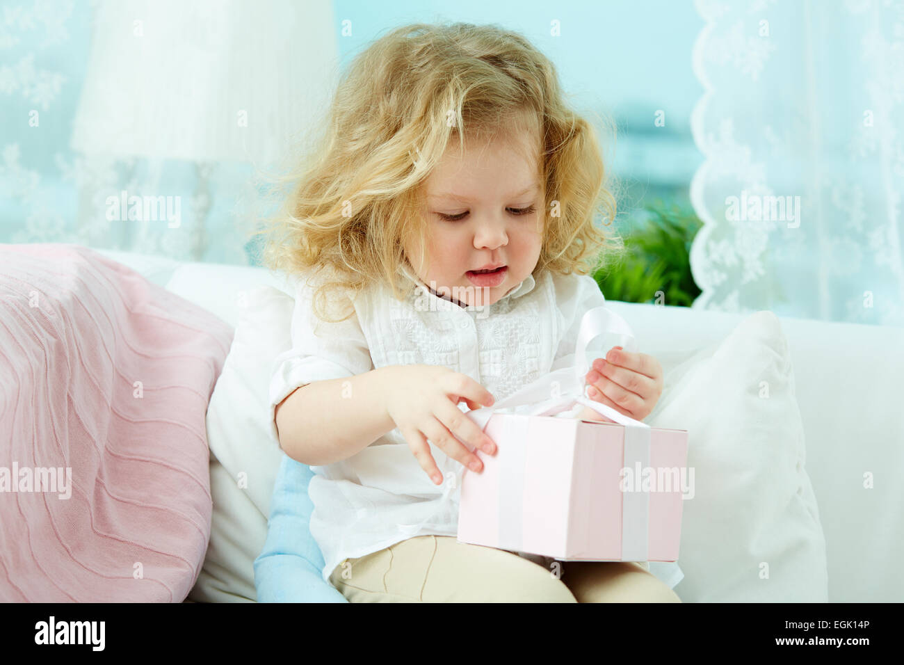 Cute little girl unpacking her gift Stock Photo - Alamy