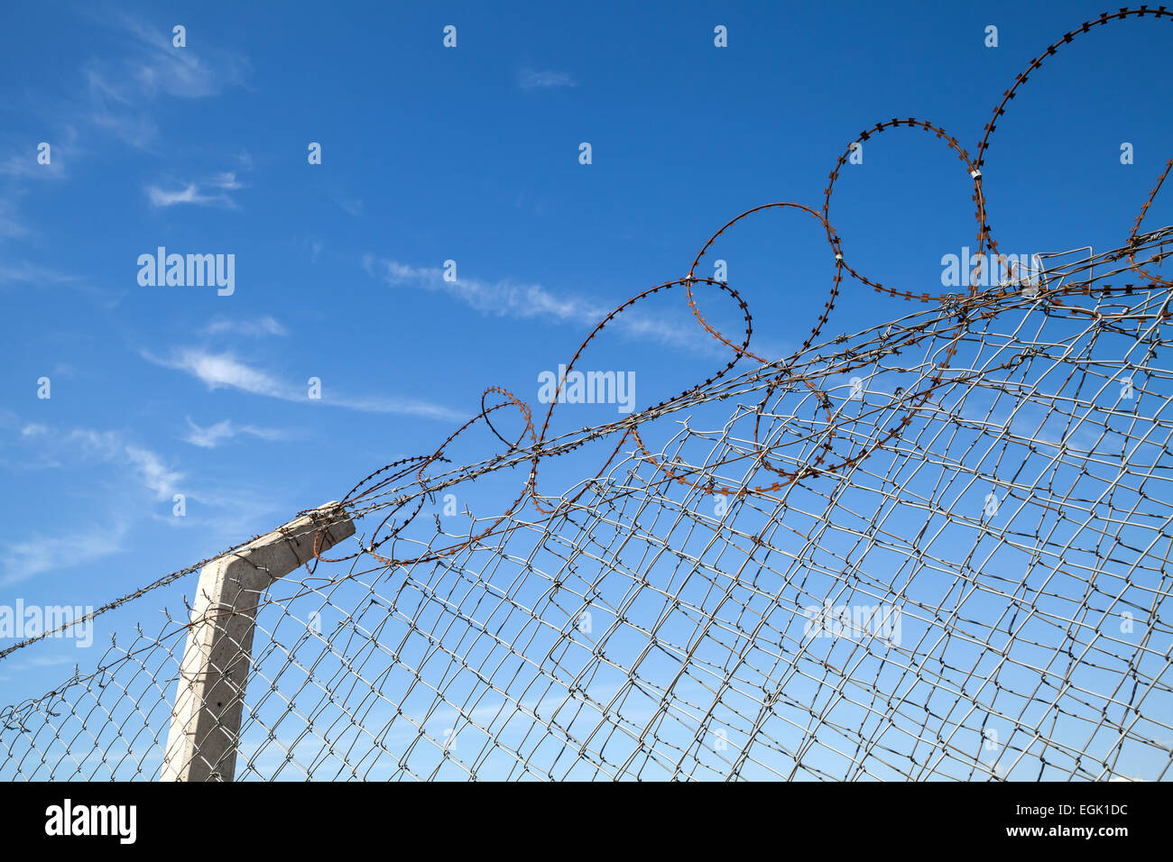 Metal fence with barbed wire over blue sky background Stock Photo - Alamy