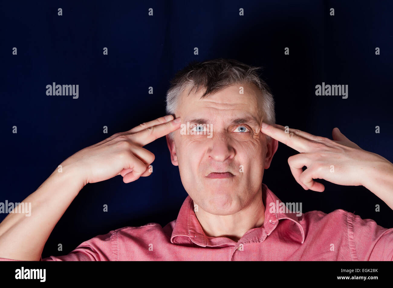 Studio portrait of a man pointing hand gun at his own head, concept of desperation Stock Photo