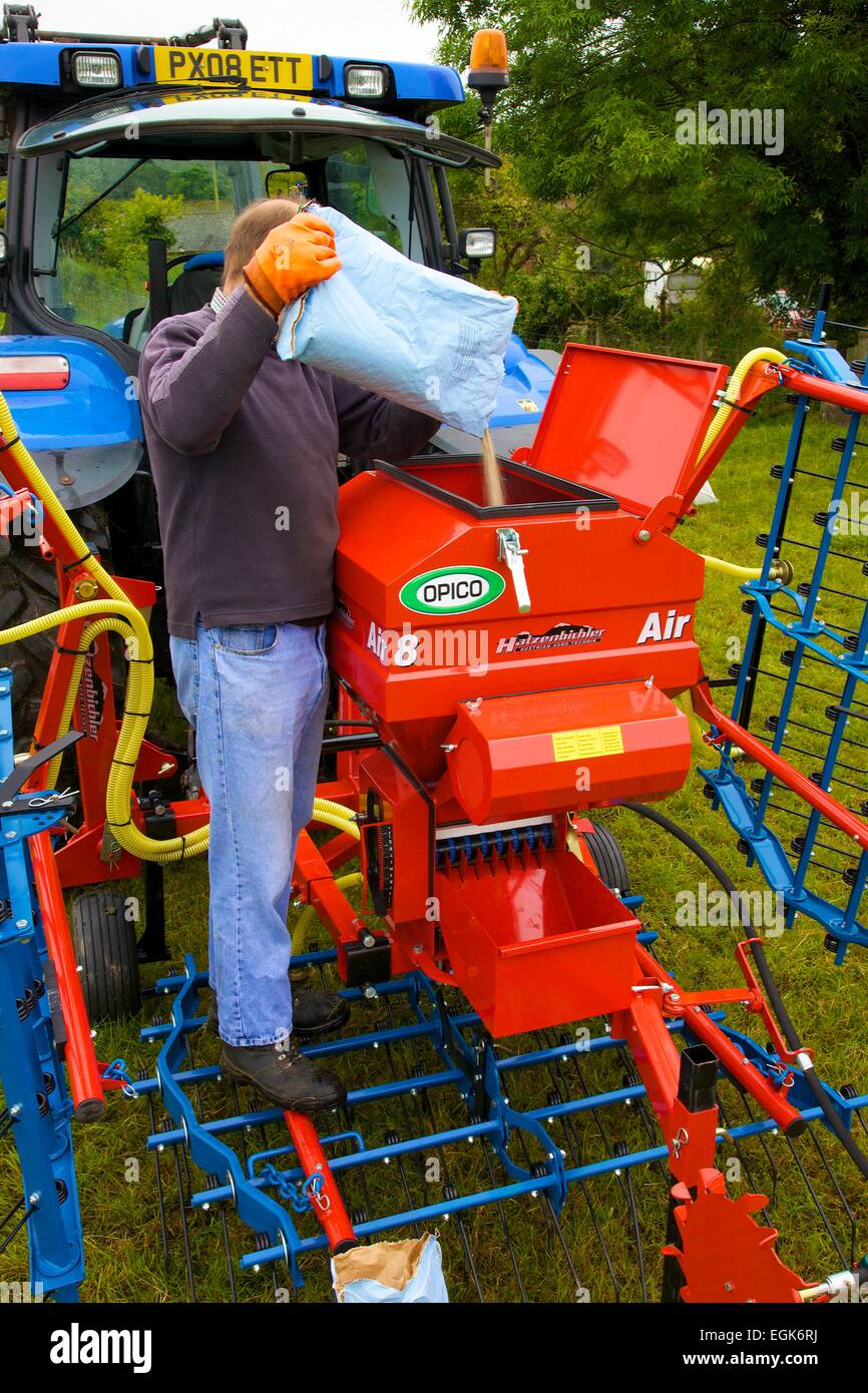 Farmer pouring clover seed into Hatzenbichler Air 8 Pneumatic Seeder & Tractor Stock Photo