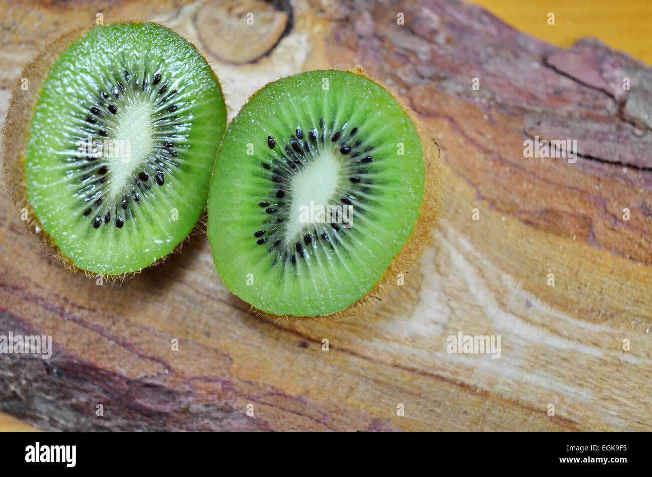 Juicy halved kiwi on a rustic wooden table Stock Photo