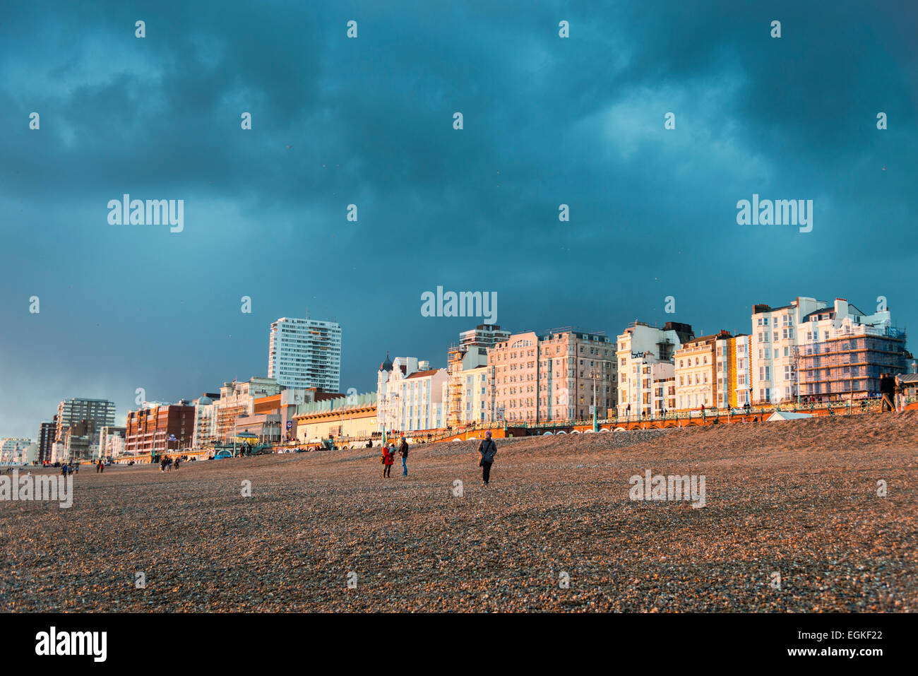 Sun lighting the beach, hotels and buildings on the seafront at Brighton on a stormy evening and a black cloudy sky Stock Photo