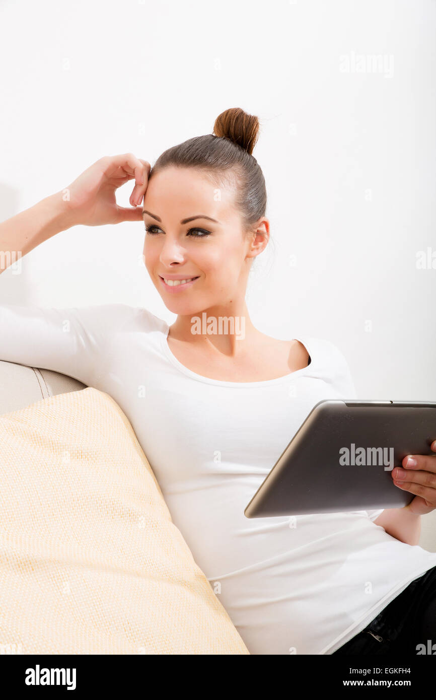 A young woman sitting on the sofa holding a tablet Stock Photo - Alamy