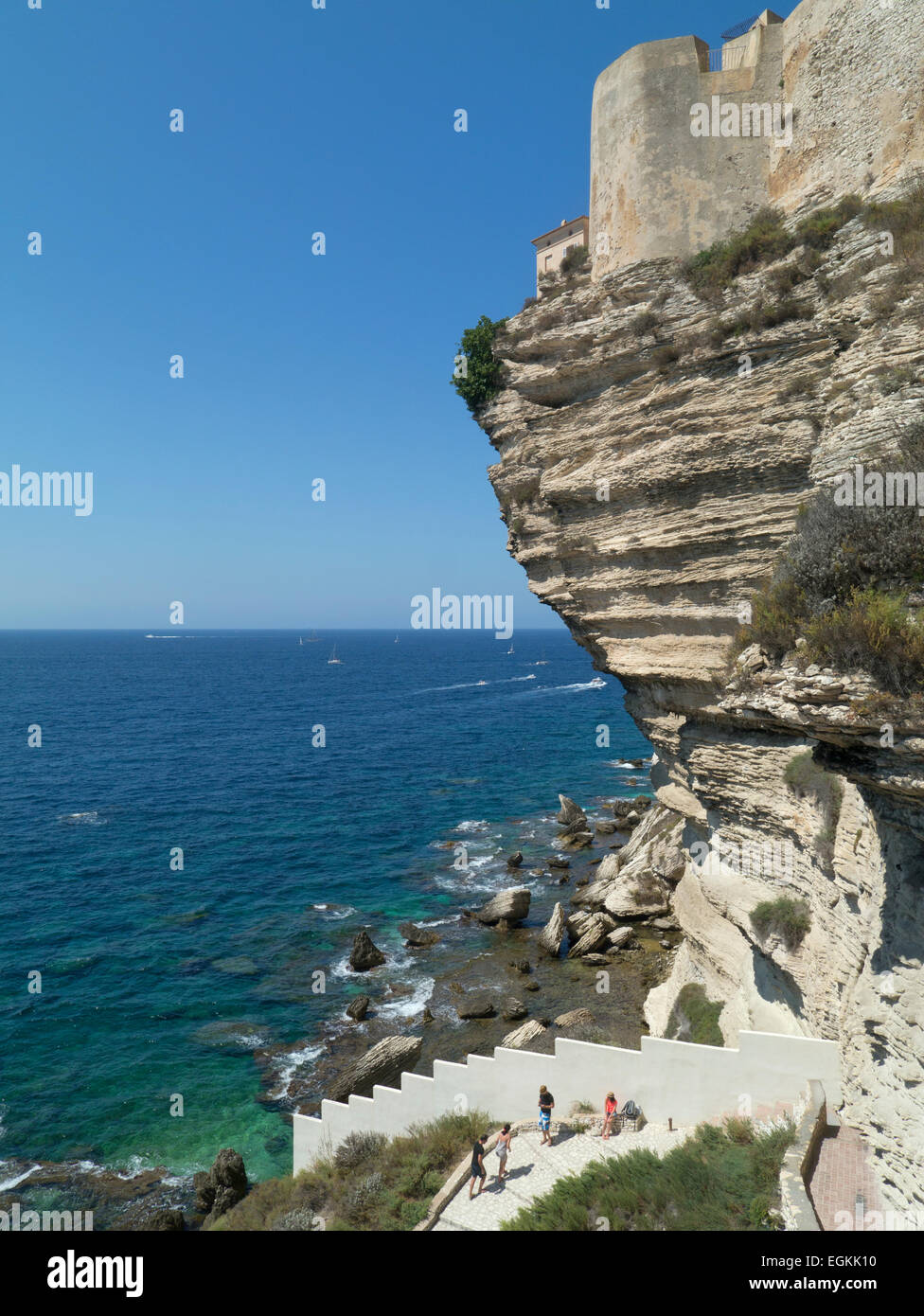 Tourists climbing sea cliff path beneath fortified old town of Bonifacio, Corsica Stock Photo