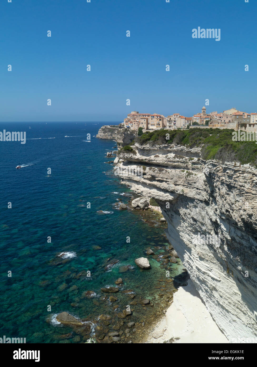 Old fortified Town of Bonifacio, Corsica, perched precariously on the sea cliffs, with beach and sea beneath and several boats Stock Photo
