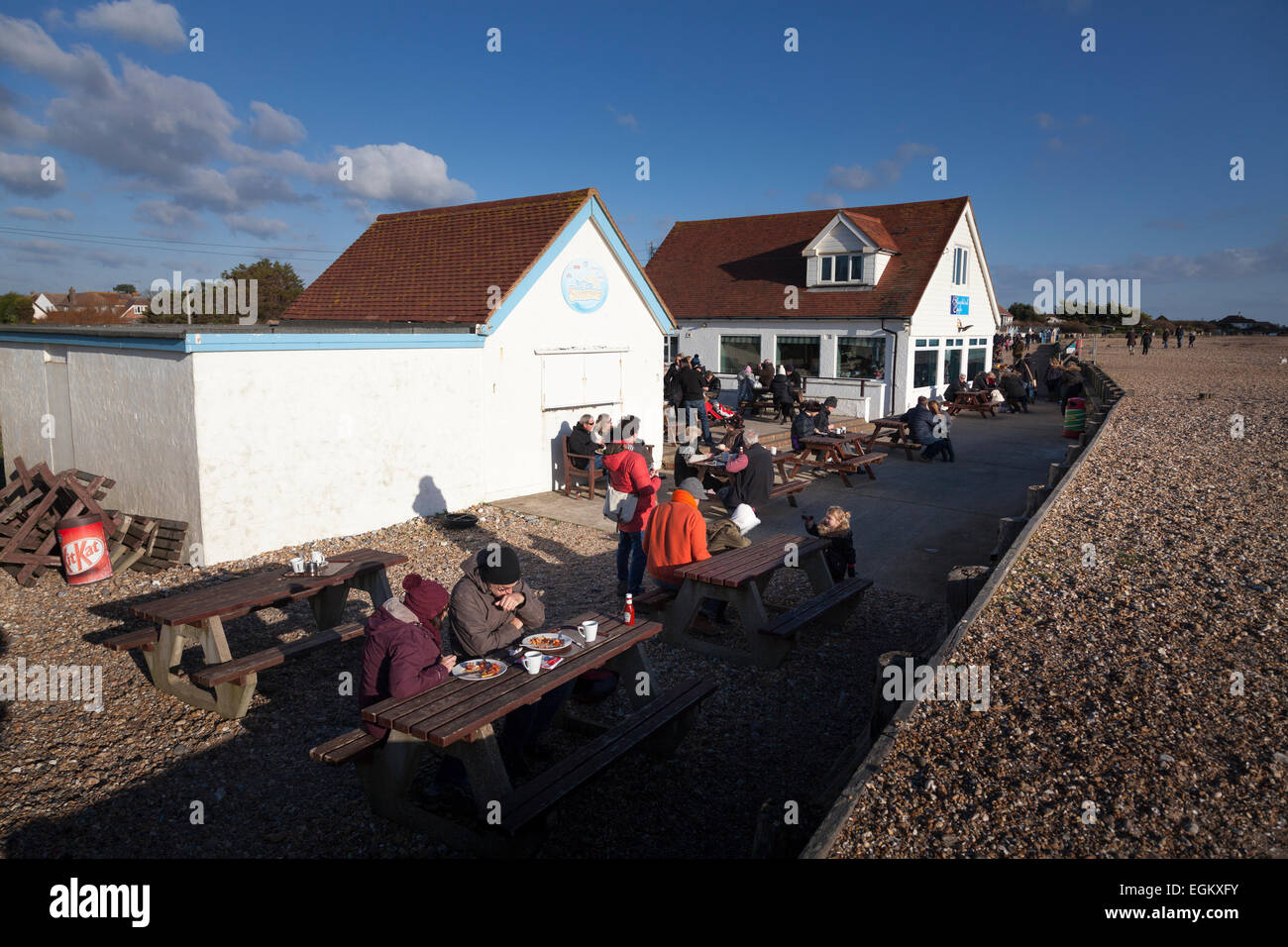 Customers sitting outside the Bluebird beach cafe on Ferring beach in the winter sunshine Stock Photo