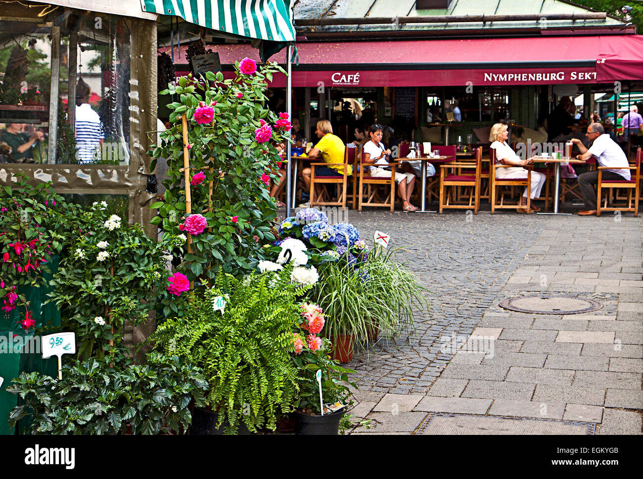 An open air coffee near a flowers stall offers leisure to the shoppers of the Viktualienmarkt,  famous market in Munich center Stock Photo