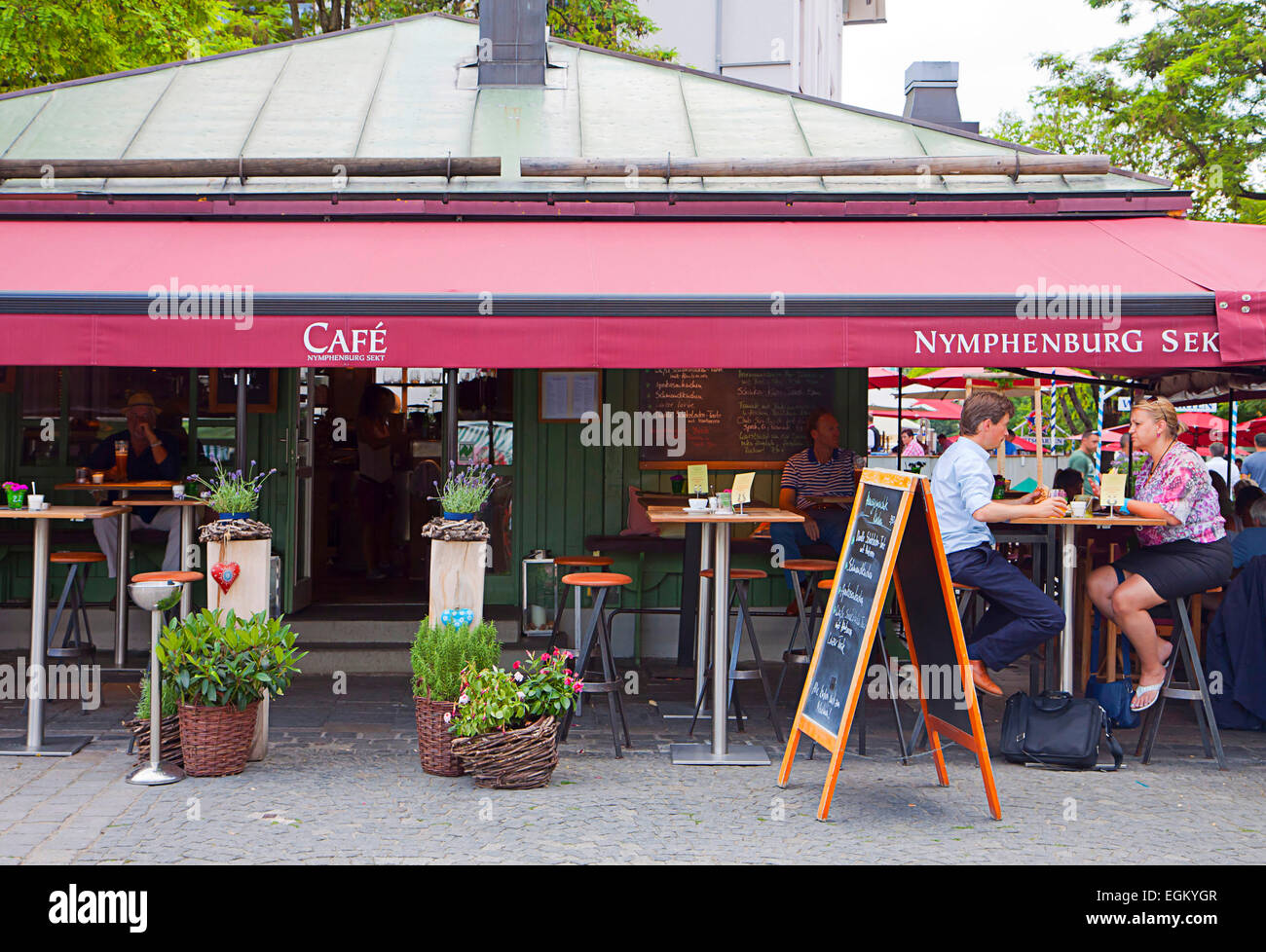 Munich, Germany - People relax  sitting at an open air coffee at Viktualienmarkt in city center, hot spot for gourmet shoppers. Stock Photo