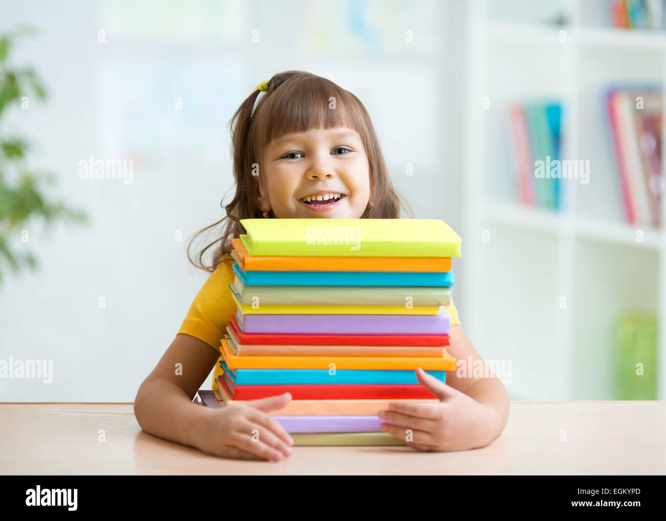 Happy little girl with a stack of books Stock Photo