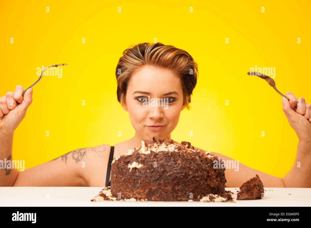 Young woman about to eat a large chocolate cake. Stock Photo