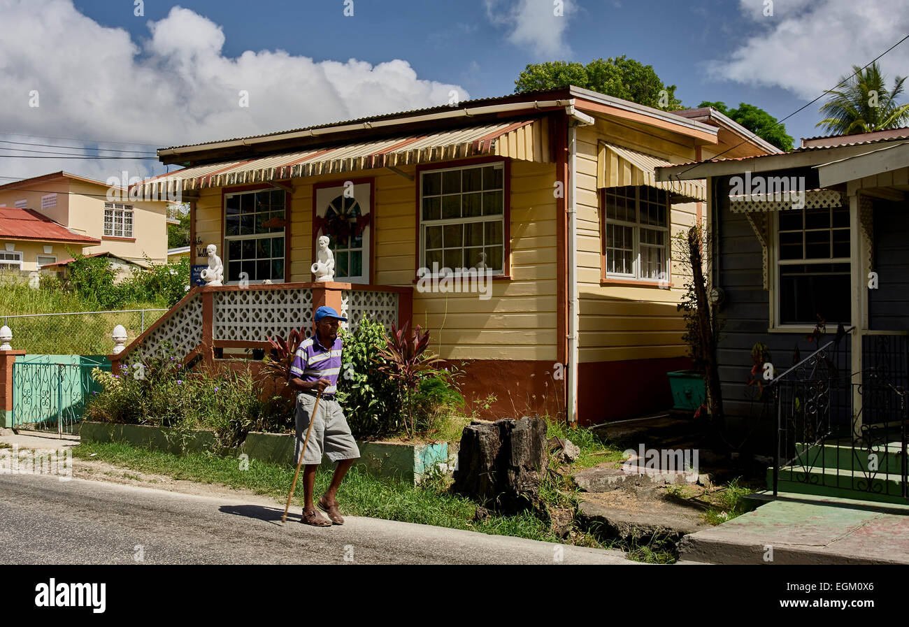 Barbados, street, wooden house, man walking towards camera, blue sky
