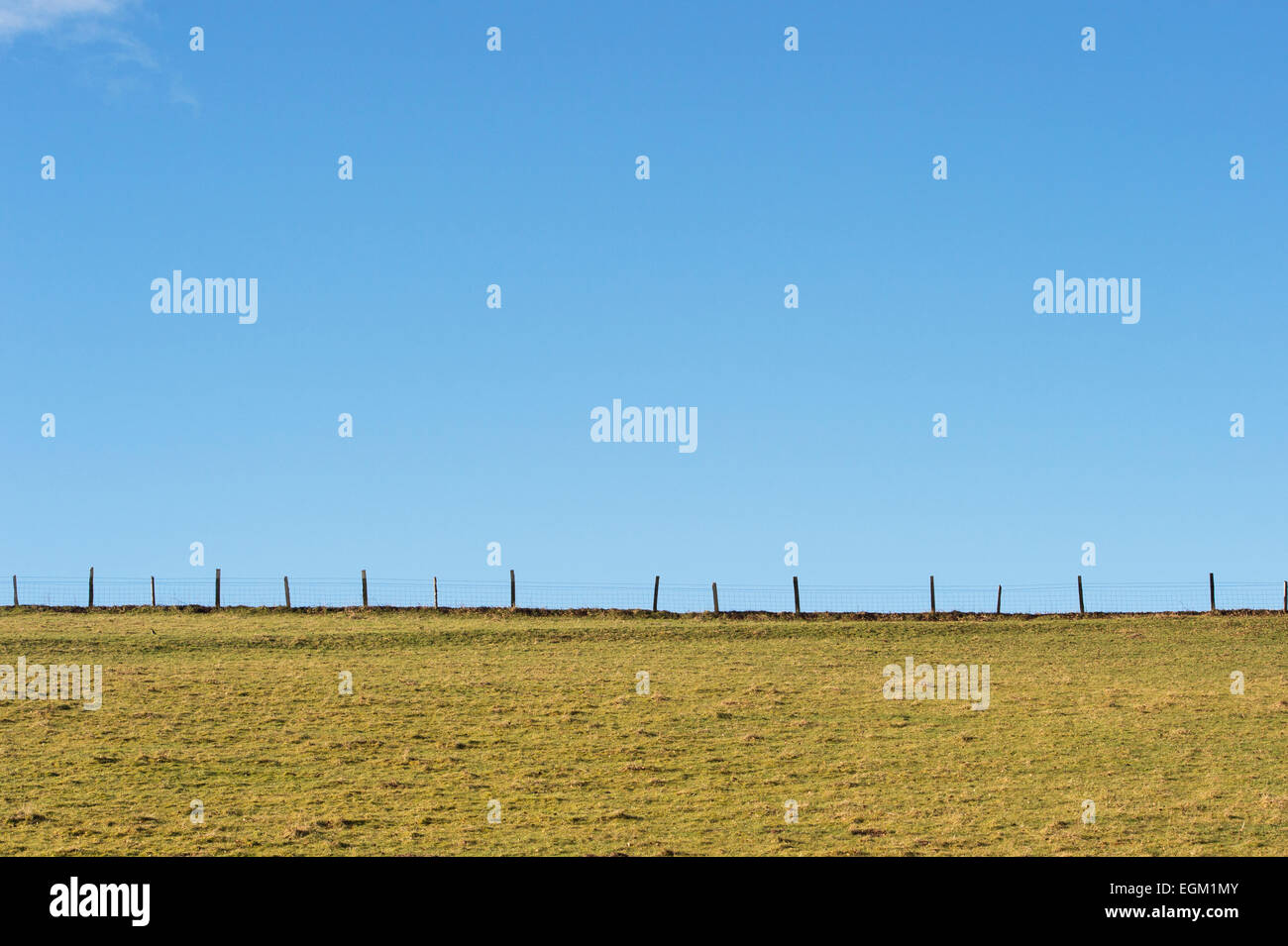 Fence line in a field with blue sky Stock Photo
