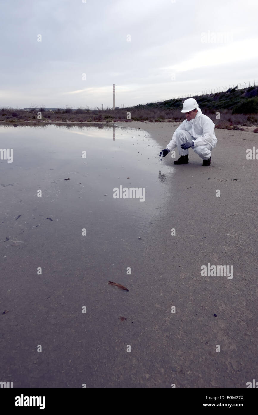 Worker in a protective suit examining pollution in the water at the industry. Stock Photo