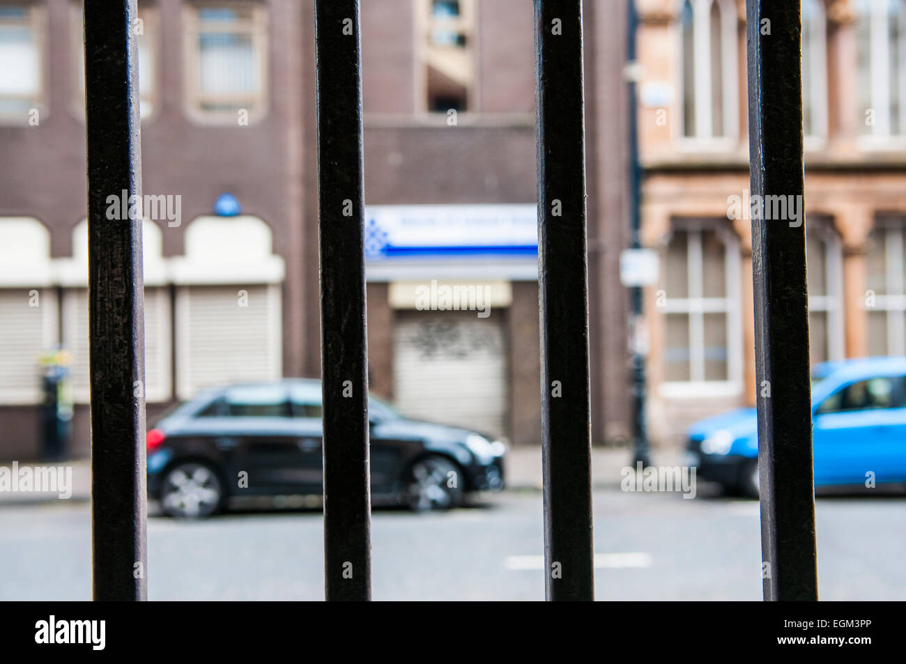 Looking through a set of bars onto a city street Stock Photo