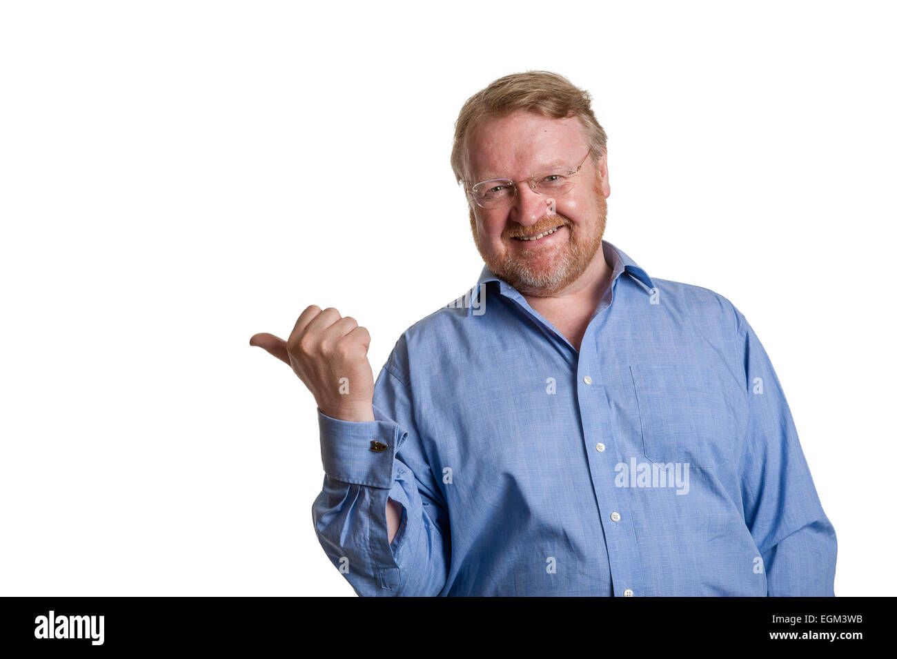 Friendly middle aged bearded guy in blue shirt indicates with thumb - on white Stock Photo