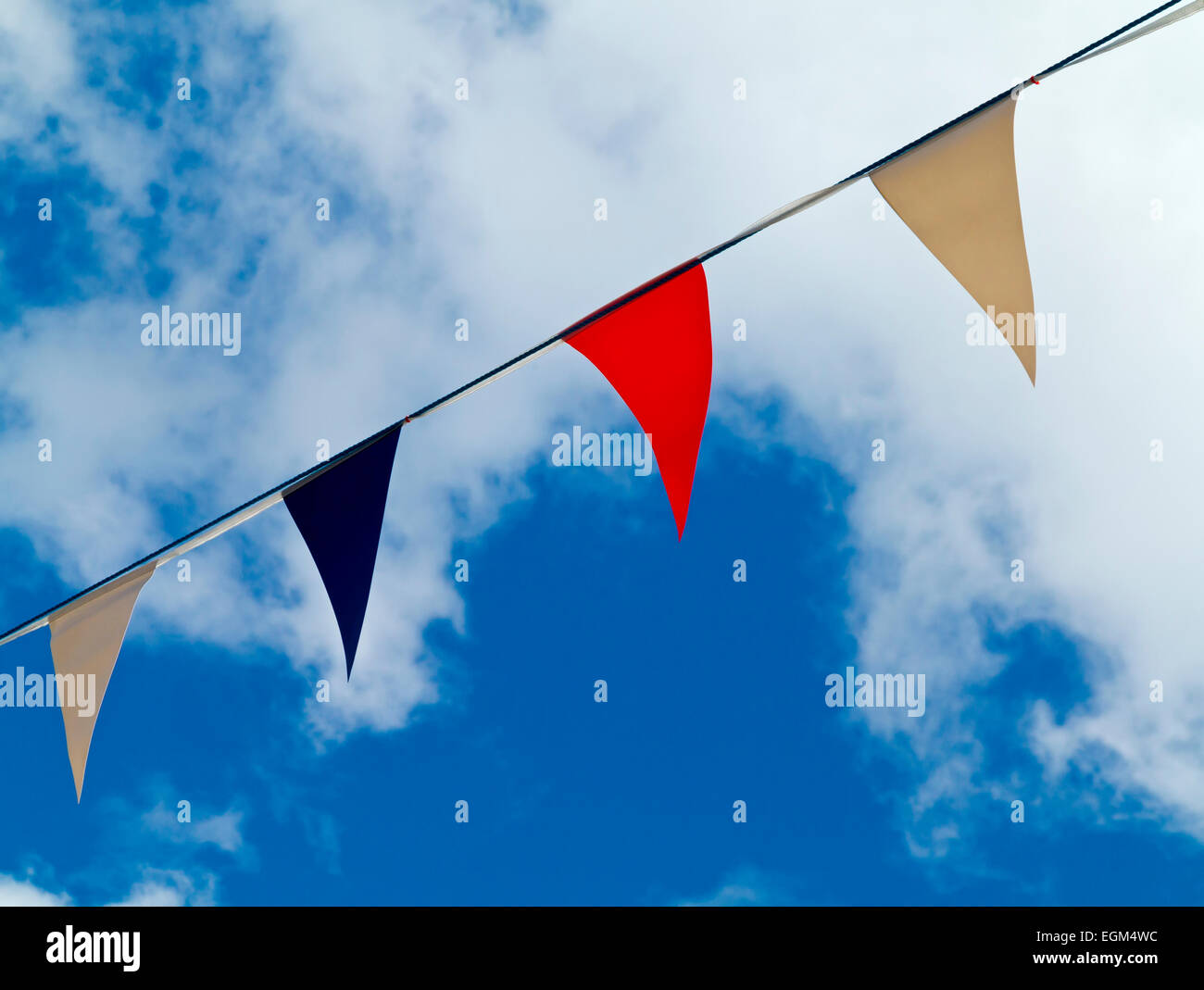 Red white and blue bunting against a blue sky with white clouds in summer Stock Photo