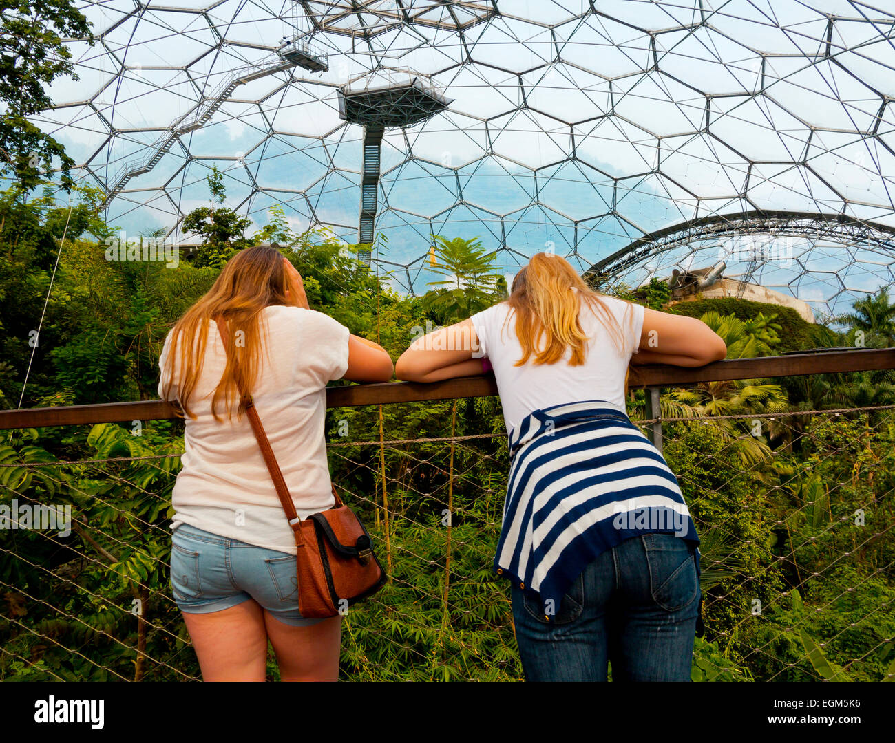 Two girls inside geodesic biome domes at the Eden Project near St Austell Cornwall England UK designed by Nicholas Grimshaw 2001 Stock Photo
