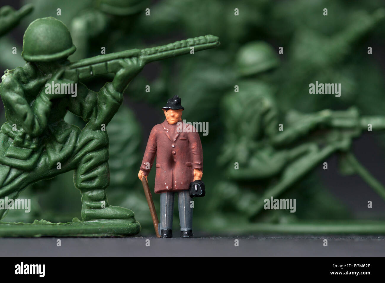 A miniature scale model figure standing amongst a set of green toy soldiers. Stock Photo