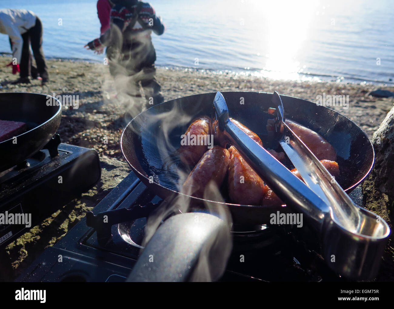Cook out at lakeside frying sausages Stock Photo - Alamy