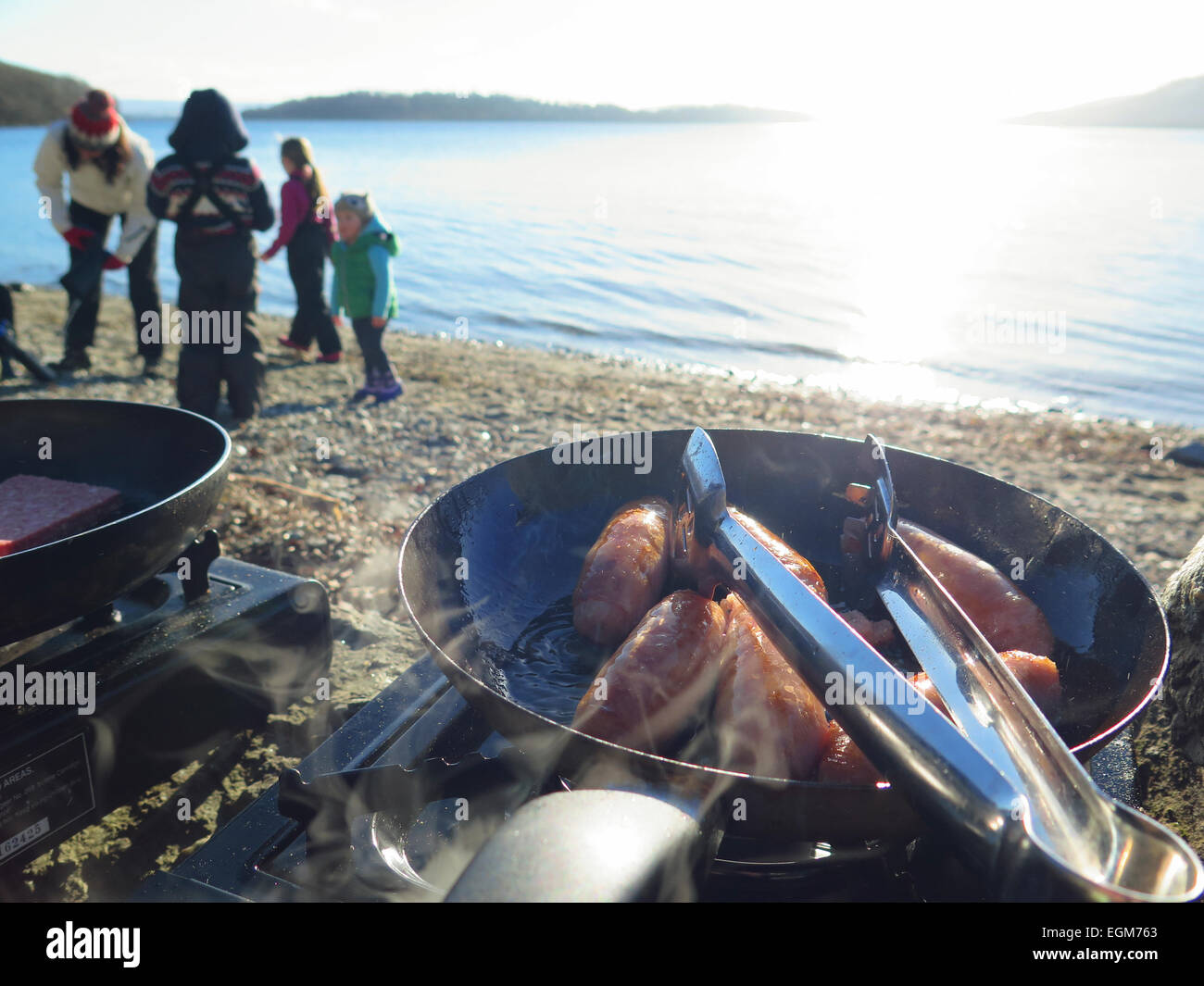 Cook out at lakeside frying sausages Stock Photo - Alamy